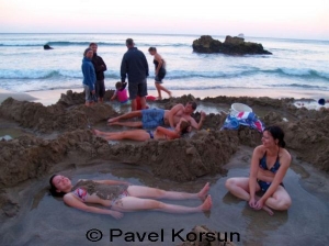 Девушки наслаждаются горячей водой из подводных вулканических источников на пляже